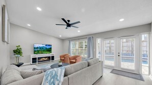 Ein modernes Wohnzimmer mit einer Couch, einem Fernseher und einem Deckenventilator.