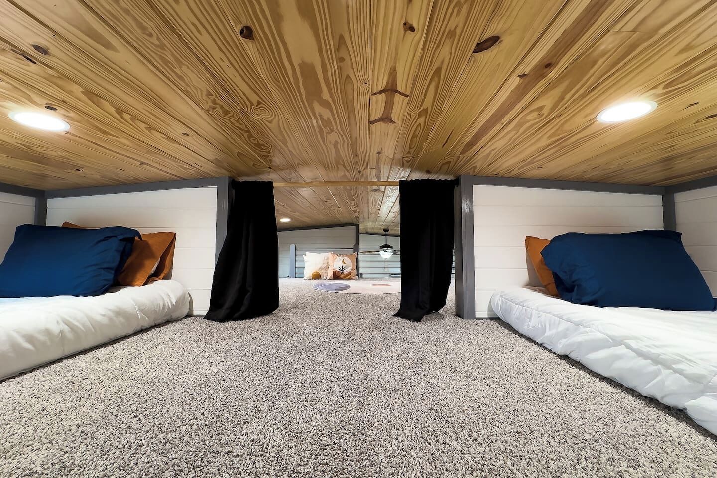 A room with two beds, a wooden ceiling, and a carpeted floor.