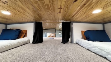 A room with two beds, a wooden ceiling, and a carpeted floor.