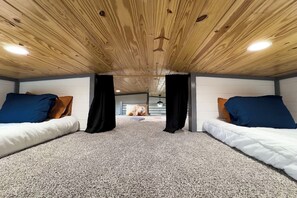 A room with two beds, a wooden ceiling, and a carpeted floor.