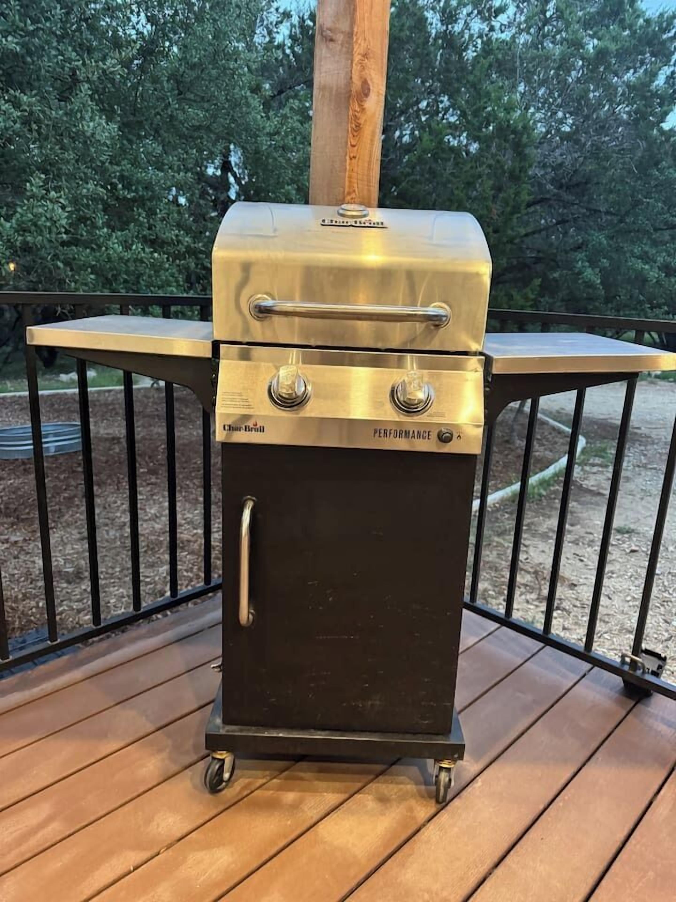 En Char Broil Performance grill på en træterrasse med gelænder i metal.