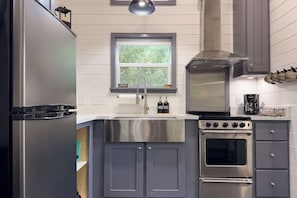 A modern kitchen with stainless steel appliances, a window above the sink, and a built-in oven. - Rustic & Private 5 Acres- Hot Tub, Fire Pit, Grill (Canyon Lake)