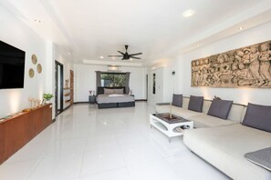 A modern living room with a large sofa, a coffee table, and a bed in the background. - Moonview at Paradise Village (Nathon (Ang Thong) Hills, koh Samui)
