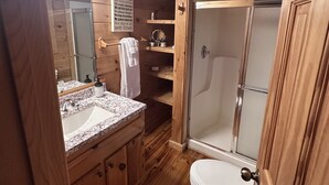 A wooden cabin bathroom with a vanity, sink, mirror, and a shower enclosure. - Rustic Cabin with Long Range Mountain Views - Hot Tub - Fire Pit (Blue Ridge)
