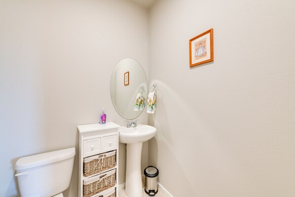 Une salle de bain équipée de toilettes, d’un lavabo, d’un miroir et d’une poubelle.