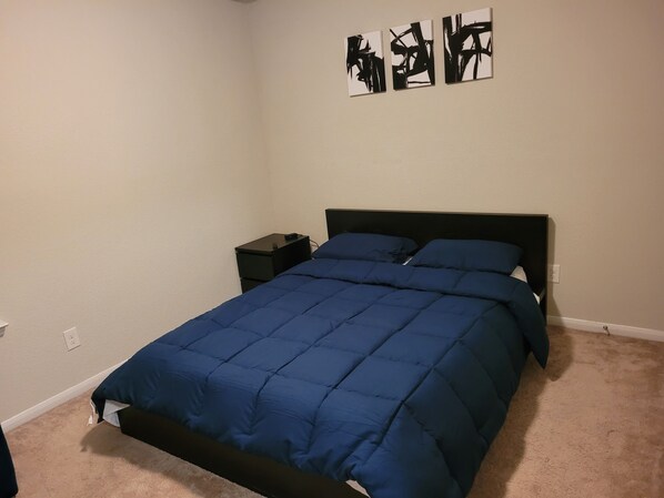 Un dormitorio con una cama, una mesita de noche y tres cuadros abstractos en la pared.
