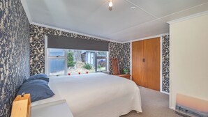 Un dormitorio con una cama grande, un armario de madera, una ventana con vistas al exterior y un papel tapiz estampado.