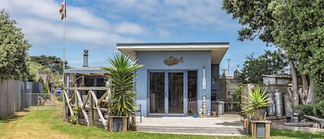 A modern house with a fish mural, a fenced yard, and potted plants.