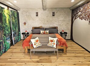 A bedroom with a bed, two nightstands, a wall mural, and a wooden floor.