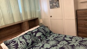 Un dormitorio con una cama, cabecera de madera, armario y ventana con cortinas.
