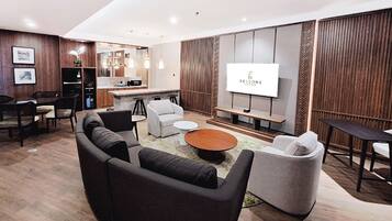 A modern living room with a sofa, armchairs, a coffee table, and a TV screen.