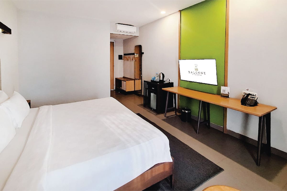 Hotellihuone, jossa on sänky, työpöytä, tuoli, televisio ja minibaari.