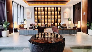 A modern lobby with a central water feature, seating areas, and a wall of illuminated shelves. - The Balcone Hotel & Resort (Bukittinggi)