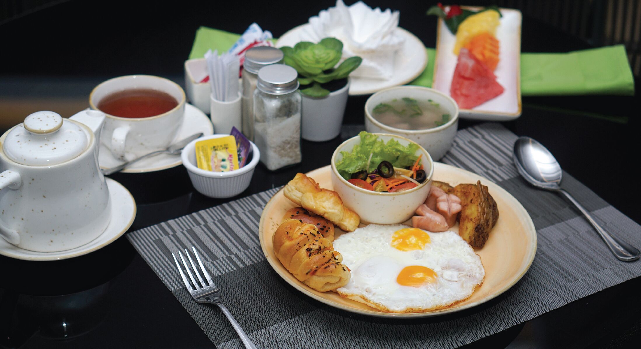 A breakfast plate with eggs, ham, potatoes, and a salad.