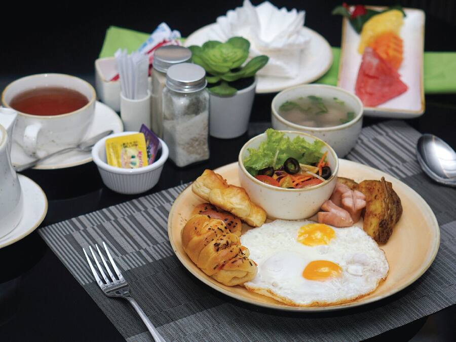 Een ontbijt bord met eieren, ham, aardappelen en een salade.
