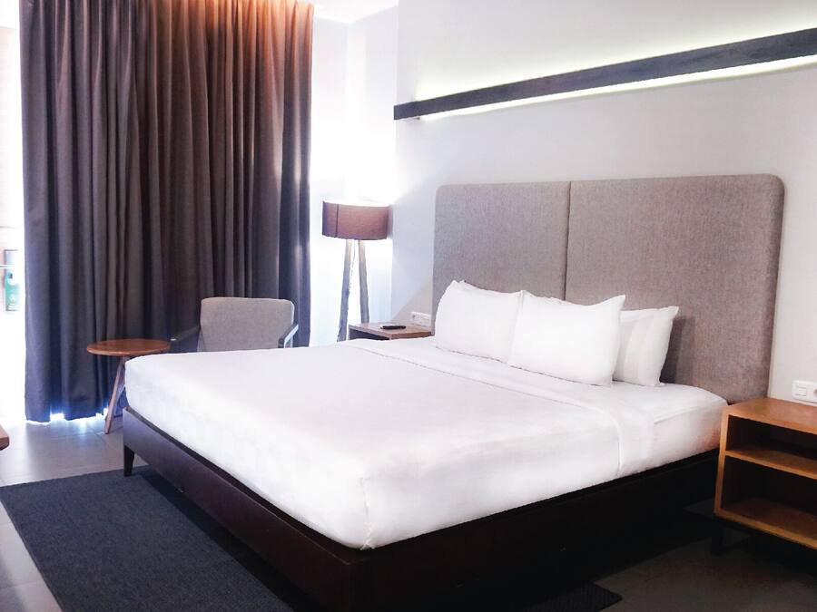 A hotel room with a large bed, a desk, a chair, and a nightstand.