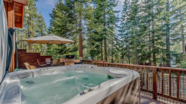 A hot tub on a wooden deck with a view of tall trees. - Spacious Pet-Friendly Truckee Retreat with Hot Tub (Truckee)
