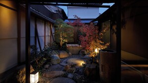 A traditional Japanese garden with a wooden structure, rocks, and a lantern. - Enso Machiya (Kyoto)