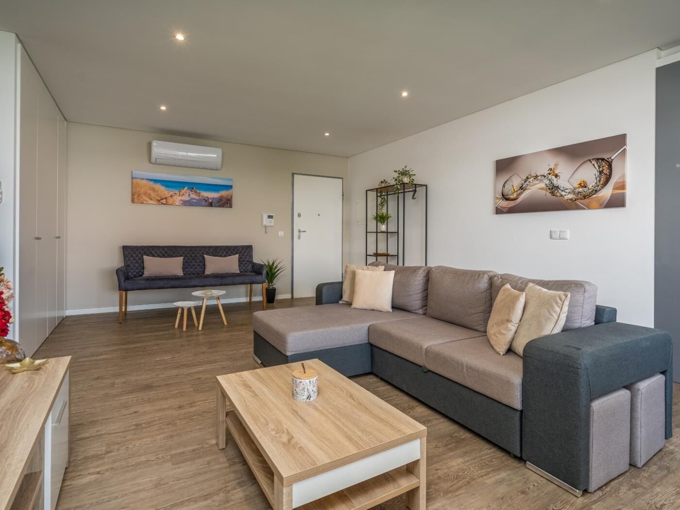 Ein modernes Wohnzimmer mit einem grauen Ecksofa, einem Holztisch und einem Bild an der Wand.