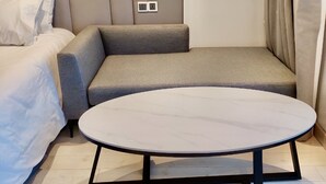 Ein modernes Schlafzimmer mit einem Bett, einem Schlafsofa, einem kleinen Tisch und einer Wandsteckdose.