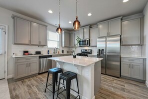 A modern kitchen with stainless steel appliances, a central island, and pendant lighting. - Spacious Cozy 3BR Retreat - Great Bedroom View (Austin)