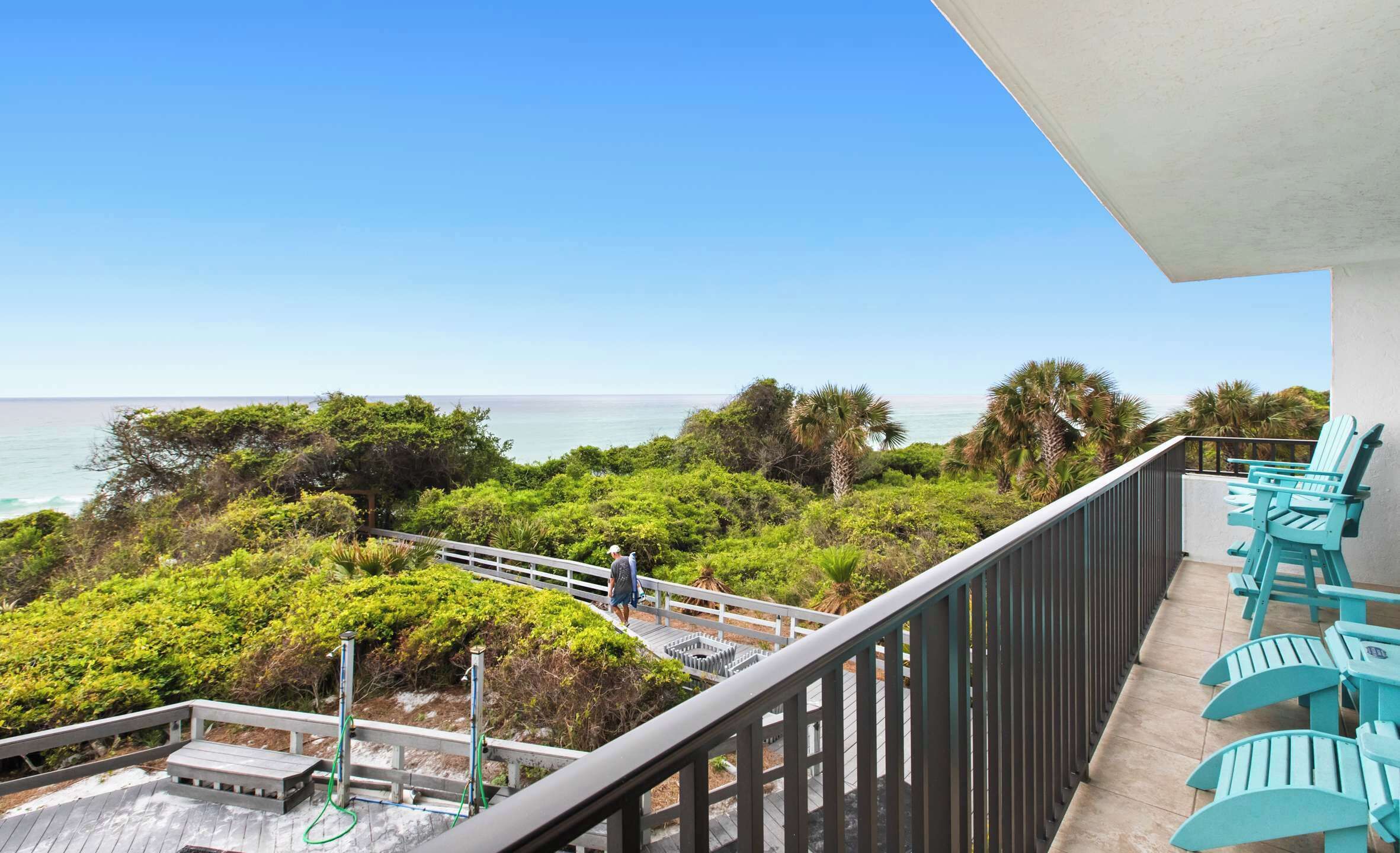 A balcony with turquoise chairs and a view of the ocean.