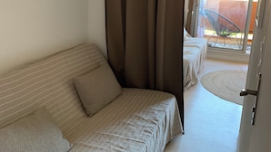 Une chambre avec un lit, un canapé, des rideaux et une vue sur le balcon extérieur.