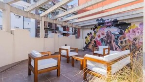 Terraza en la azotea con muebles de madera y un mural colorido.