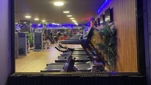 Une salle de sport équipée de tapis de course, d’appareils de musculation et de tapis de sol pour les exercices.