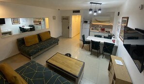 Um espaço de estar compacto com sofá, mesa de jantar e cozinha compacta.