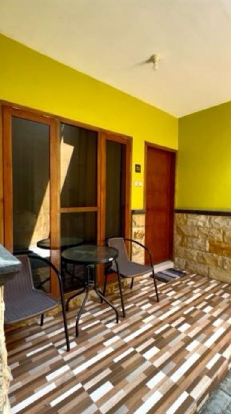 A room with a wooden floor, a table with chairs, and a yellow wall.