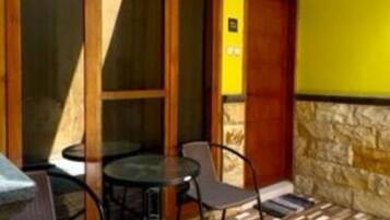 A room with a wooden floor, a table with chairs, and a yellow wall.