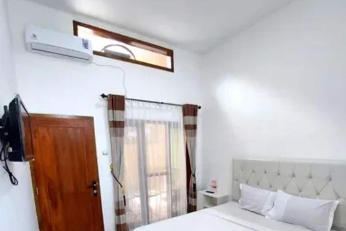 A bedroom with a large bed, a wooden door, and a window with curtains.