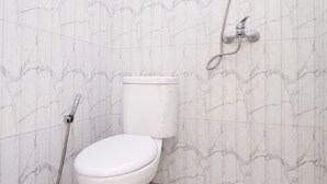 A bathroom with a toilet, a shower, and a marble-patterned wall. - Sandi Guest House Syariah (Banyuwangi)