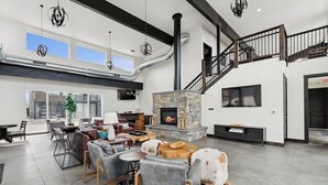 A spacious living area with a fireplace, leather furniture, and a staircase. - New Build, Pool, 1 bed 1 bath Condo at the Quarry (Whitefish)