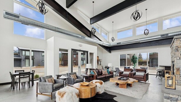 A spacious living room with a fireplace, leather sofas, and a large rug. - New Build, Pool, 1 bed 1 bath Condo at the Quarry (Whitefish)