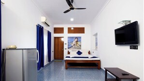 Ein Schlafzimmer mit einem Bett, einem Fernseher, einem Deckenventilator und einem kleinen Tisch.