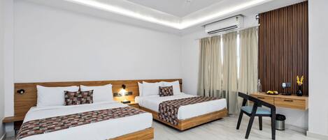 A hotel room with two beds, a desk, and an air conditioning unit.