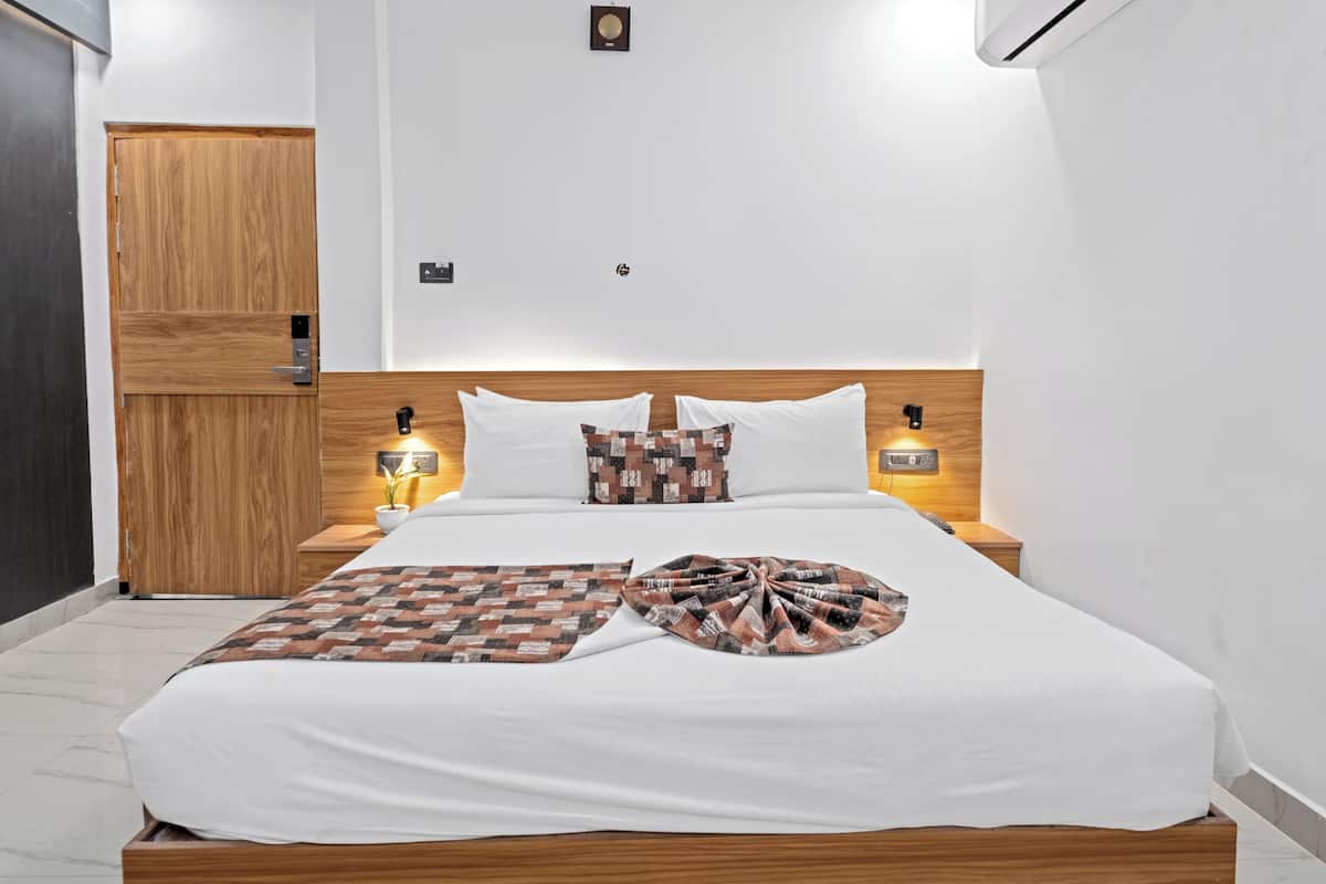 Una cama bien hecha con un edredón estampado, lámparas de noche y un cabecero de madera.