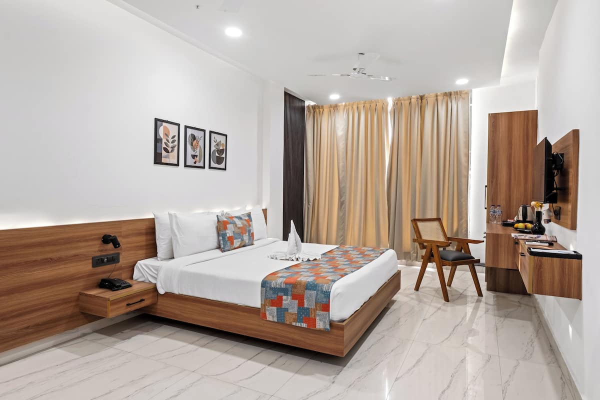 Una habitación de hotel moderna con una cama de madera, un escritorio con una silla y un televisor montado en la pared.