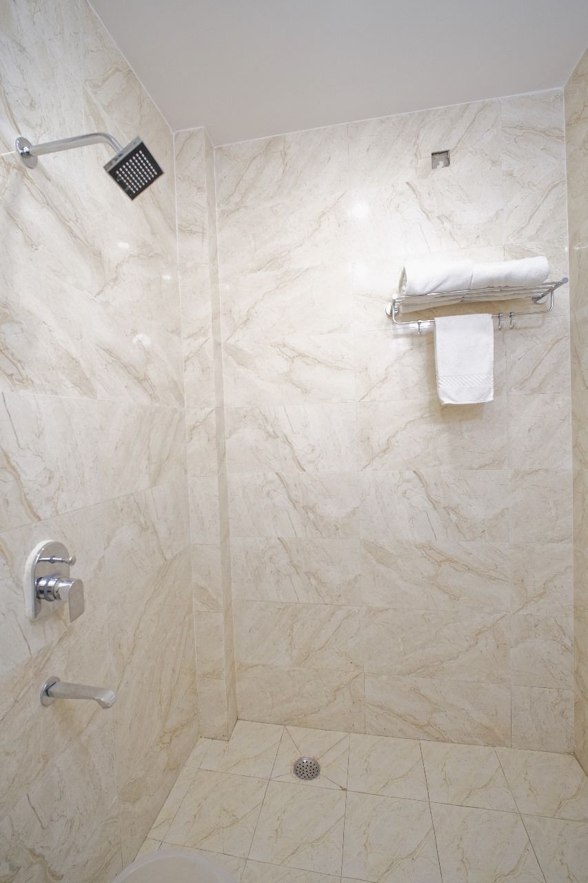 A walk-in shower with a handheld showerhead, a towel rack with a folded towel, and a floor drain.
