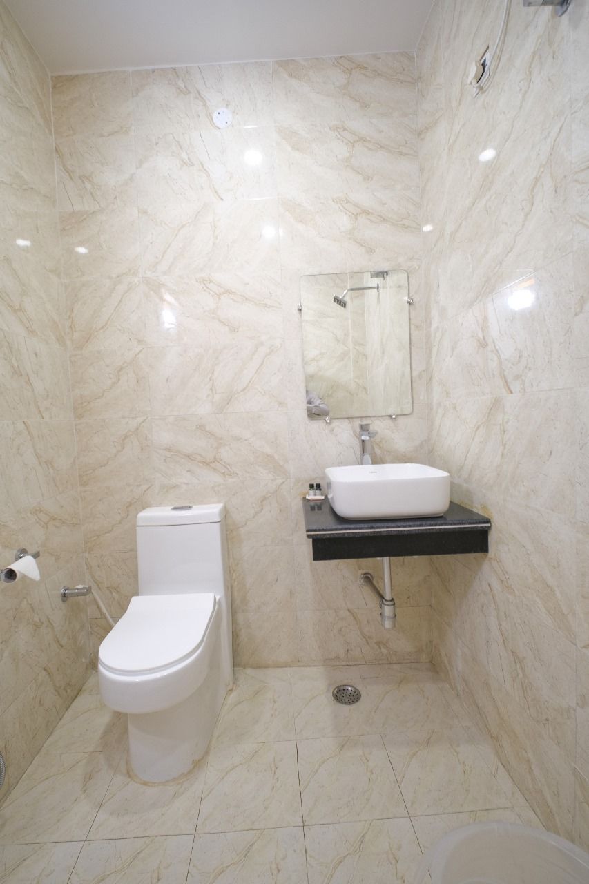 Un baño con inodoro, lavabo, espejo y paredes de mármol.