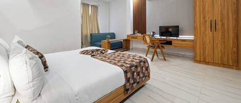 Una habitación de hotel moderna con una cama grande, un escritorio con computadora, un armario y una ventana con cortinas.