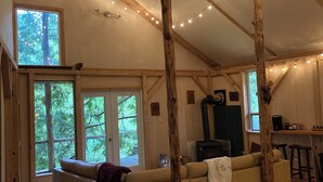 A cozy interior with a wooden floor, a sofa, and a dining area. - Unique Cortes Treehouse! - Peaceful haven in the trees (Strathcona B)