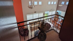 A spacious living area with a high ceiling, multiple windows, and a balcony with outdoor seating. - Luxury Home with Pool, Gym & EV Charger – Prime Location in Querétaro (Santiago de Querétaro)