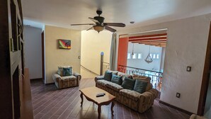 A spacious living room with a ceiling fan, a sofa set, a coffee table, and a painting on the wall. - Luxury Home with Pool, Gym & EV Charger – Prime Location in Querétaro (Santiago de Querétaro)