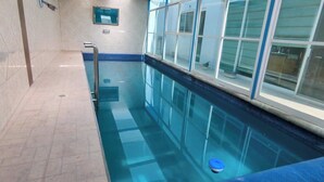 A swimming pool with clear blue water, a metal ladder, and a window with a view of the outside. - Luxury Home with Pool, Gym & EV Charger – Prime Location in Querétaro (Santiago de Querétaro)