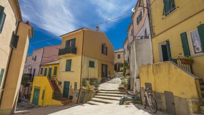 Une rue étroite, bordée de bâtiments des deux côtés, avec un escalier menant à un niveau supérieur et un vélo garé sur le côté droit.