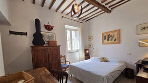 Une chambre confortable avec un lit, une commode en bois, une table à manger et une guitare.