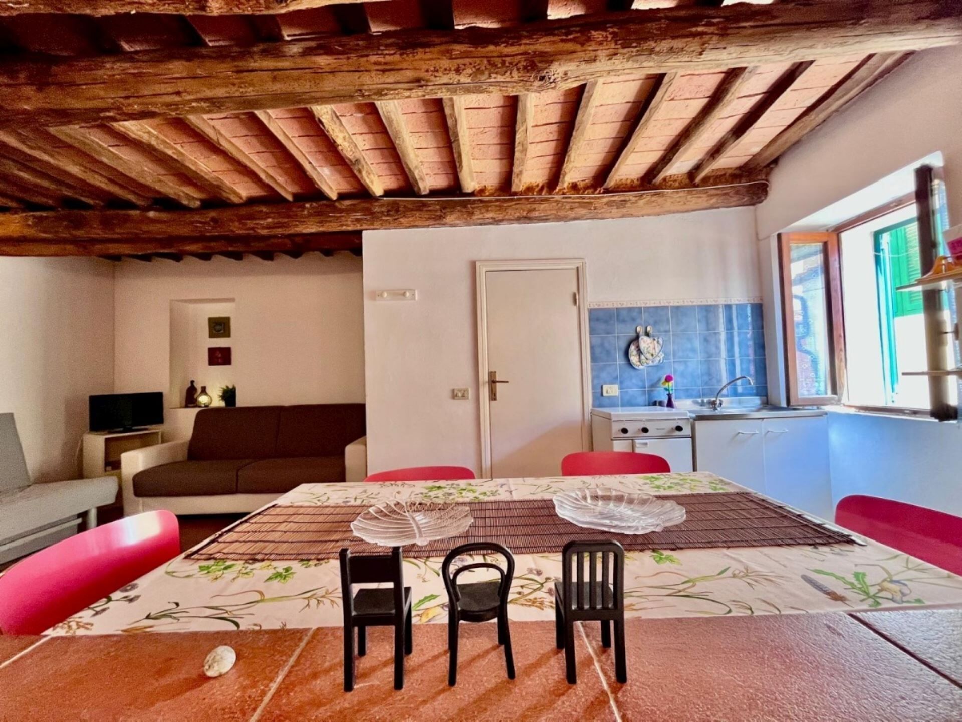 A cozy kitchen with a tiled backsplash, a dining area with a table set for four, and a wooden ceiling.